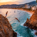Clavadista de La Quebrada saltando al mar frente a la bahía de Acapulco al atardecer, con la ciudad iluminándose al fondo.